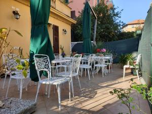 un patio con tavoli e sedie bianchi e ombrelloni verdi di Sabini Rentals - Affittacamere a Santa Margherita Ligure