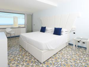 ein Schlafzimmer mit einem großen weißen Bett mit blauen Kissen in der Unterkunft Hotel Villa Felice Relais in Amalfi
