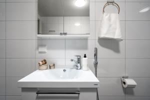 a white bathroom with a sink and a mirror at Roost Rantatie 18 in Tampere
