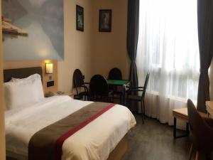 une chambre d'hôtel avec un lit, une table et des chaises dans l'établissement Thank Inn Chain Hotel sichuan luzhou longmatan district kaixuan city, à Luzhou