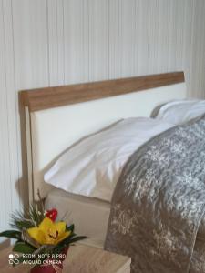 Bett mit einem Kopfteil aus Holz und Blumen auf dem Tisch in der Unterkunft Niš Downtown Residence in Niš