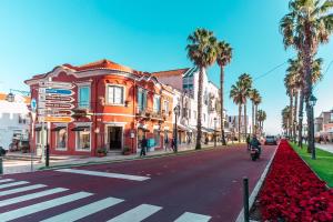a street in a city with palm trees and a man riding a motorcycle at Wine Inn Cascais Guesthouse in Cascais