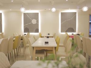 una sala da pranzo con tavoli, sedie e finestre di Thank Inn Plus Hotel Shandong Qingdao Licang Wan Nianquan Road a Qingdao