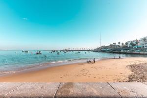 une plage avec des gens et des bateaux dans l'eau dans l'établissement Wine Inn Cascais Guesthouse, à Cascais