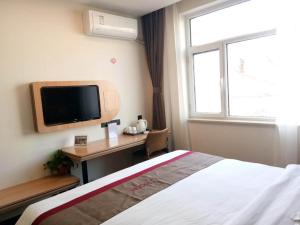 1 dormitorio con 1 cama y escritorio con TV en Thank Inn Chain Hotel hebei xingtai nanhe county tobacco bureau, en Nanhe
