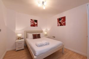 1 dormitorio con 1 cama blanca y 2 toallas en Dreamhouse Apartments Manchester City Centre, en Mánchester
