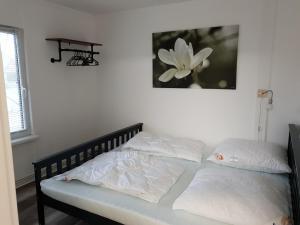 ein Bett mit weißen Kissen und einem Bild einer Blume in der Unterkunft Ferienwohnung Lindenstraße 8L in Flessenow
