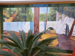une peinture murale sur le côté d'un bâtiment avec une plante dans l'établissement LUNA-Guest Rooms, à Alcalá de Guadaira