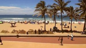 un groupe de personnes sur une plage avec des palmiers dans l'établissement North Beach Durban Apartments, à Durban