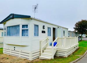 a white tiny house with a porch and stairs at Shorefield country Park, in Milford on Sea