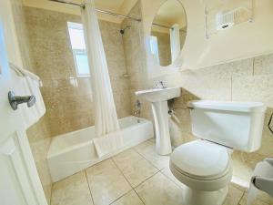 a bathroom with a toilet and a sink and a tub at A 1 A Super Inn in Ormond Beach