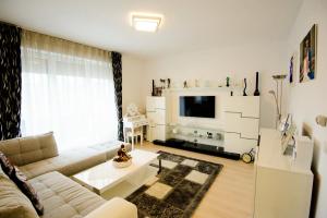 salon z białą kanapą i telewizorem w obiekcie Beatrice Apartments w Braszowie