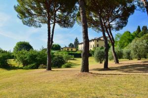 um campo com árvores e uma casa ao fundo em Villa Porta Romana - Family country house in the heart of Florence em Florença