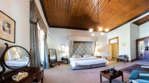 a large bedroom with a large bed and a wooden ceiling at Lord Milner Hotel in Matjiesfontein