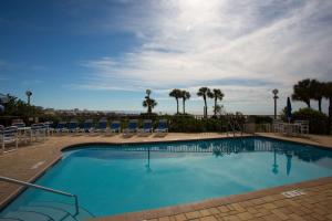a large swimming pool with chairs and palm trees at 105 - Caprice Resort in St. Pete Beach
