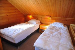 two beds in a room with wooden walls at Chalet Le Mirador in Durbuy