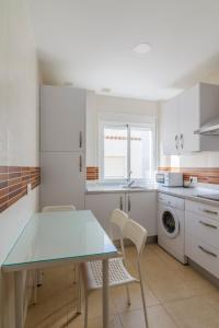 cocina con mesa, sillas y lavadora en Apartamentos Montedunas, en Barbate