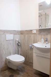 a bathroom with a white toilet and a sink at City Apartments Portico in Merano