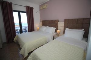a hotel room with two beds and a balcony at Julia Hotel in Sarandë