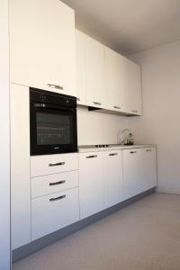 cocina con armarios blancos y microondas en City Apartments Portico, en Merano
