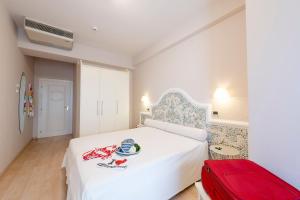 una camera con un letto bianco e una valigia rossa di Hotel Dino a San Benedetto del Tronto