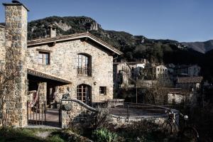 un edificio de piedra con una montaña en el fondo en Mas La Cabanya Beget Xalet de muntanya en Beget