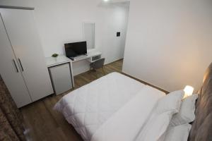 a small bedroom with a white bed and a television at Julia Hotel in Sarandë