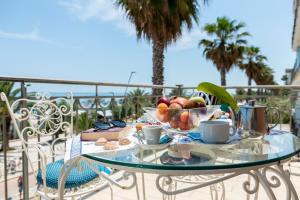 a glass table with a bowl of fruit and coffee cups at Hotel Dino in San Benedetto del Tronto