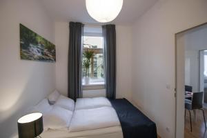 Schlafzimmer mit einem weißen Bett und einem Fenster in der Unterkunft Cozy 2 ROOM APARTMENT - Enjoy Viennas summer Vibes in Wien