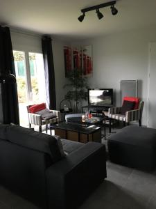 a living room with couches and a table and a tv at chambres chez Brigitte et Patrick près du Mont st Michel in Saint-Quentin-sur-le-Homme