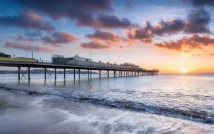 ein Pier am Strand mit Sonnenuntergang in der Unterkunft Three palms in Paignton