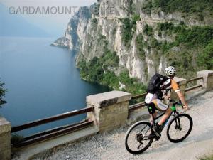 un hombre montando una bicicleta en una montaña con vistas al agua en Villa Botton d'Oro Villa al lago en Lagolo di Calavino