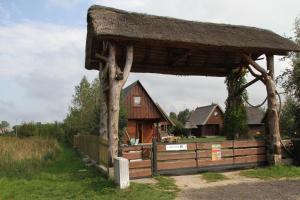 een houten paviljoen met een huis op de achtergrond bij Domki Ranczo Itrich in Łeba