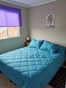 un letto blu in una camera da letto con finestra di Casa Amoblada Puerto Montt a Puerto Montt