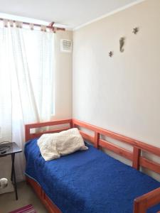 1 dormitorio con 1 cama con manta azul en Acogedor departamento cerca del mar, en La Serena