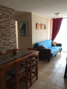 sala de estar con sofá azul y mesa en Acogedor departamento cerca del mar, en La Serena