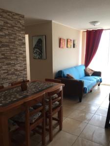 a living room with a blue couch and a table at Acogedor departamento cerca del mar in La Serena