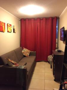 sala de estar con sofá y cortina roja en Acogedor departamento cerca del mar, en La Serena