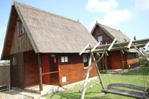 twee grote houten gebouwen met een grasdak bij Domki Ranczo Itrich in Łeba