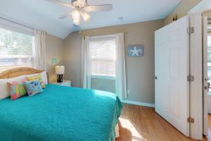 um quarto com uma cama azul e uma ventoinha de tecto em 103 - Sea Cottage em St. Pete Beach