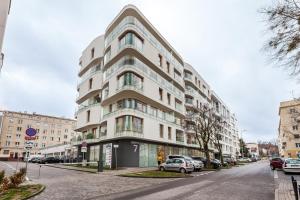 un grand bâtiment blanc avec des voitures garées devant lui dans l'établissement Apartamenty Black&White - Apartament Loft Style, à Gdynia