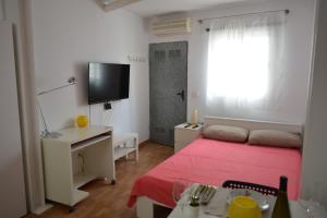 una piccola camera con letto rosso e televisore di Maspalomas Studio a Maspalomas