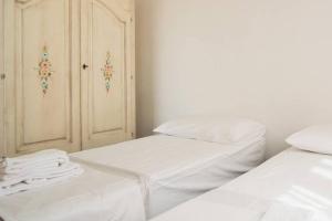 two beds in a room with white sheets and a cabinet at Agricampeggio Maccari in Casa Maccari