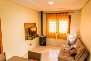ein Wohnzimmer mit einem Sofa und einem TV in der Unterkunft Cantinho do Sossego in Nova Petrópolis