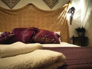 Apartamentos Alma y Montaña في كومبيتا: غرفة نوم مع سرير مع الوسائد الأرجوانية و اللوح الأمامي