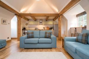 a living room with two blue couches and a kitchen at Sandford Country Cottages in Newport-On-Tay