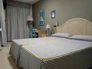 - une chambre avec un lit et un bureau avec une chaise dans l'établissement Hotel Pineda Playa, à Noja