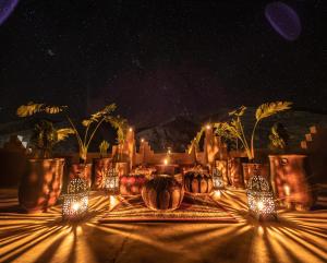 a table with vases and lights on it at night at Hotel Riad Bahammou in Aït Idaïr