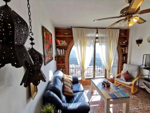 a living room with a blue leather couch and a table at Apartamentos Alma y Montaña in Cómpeta