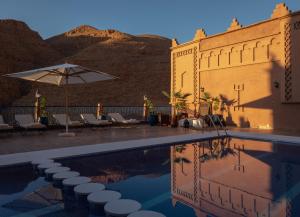 a resort with a pool and a building with a mountain at Hotel Riad Bahammou in Aït Idaïr